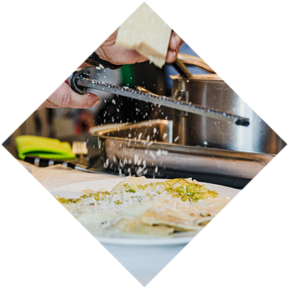 Ein Tellergericht wird mit frisch geriebenen Parmesan verfeinert.